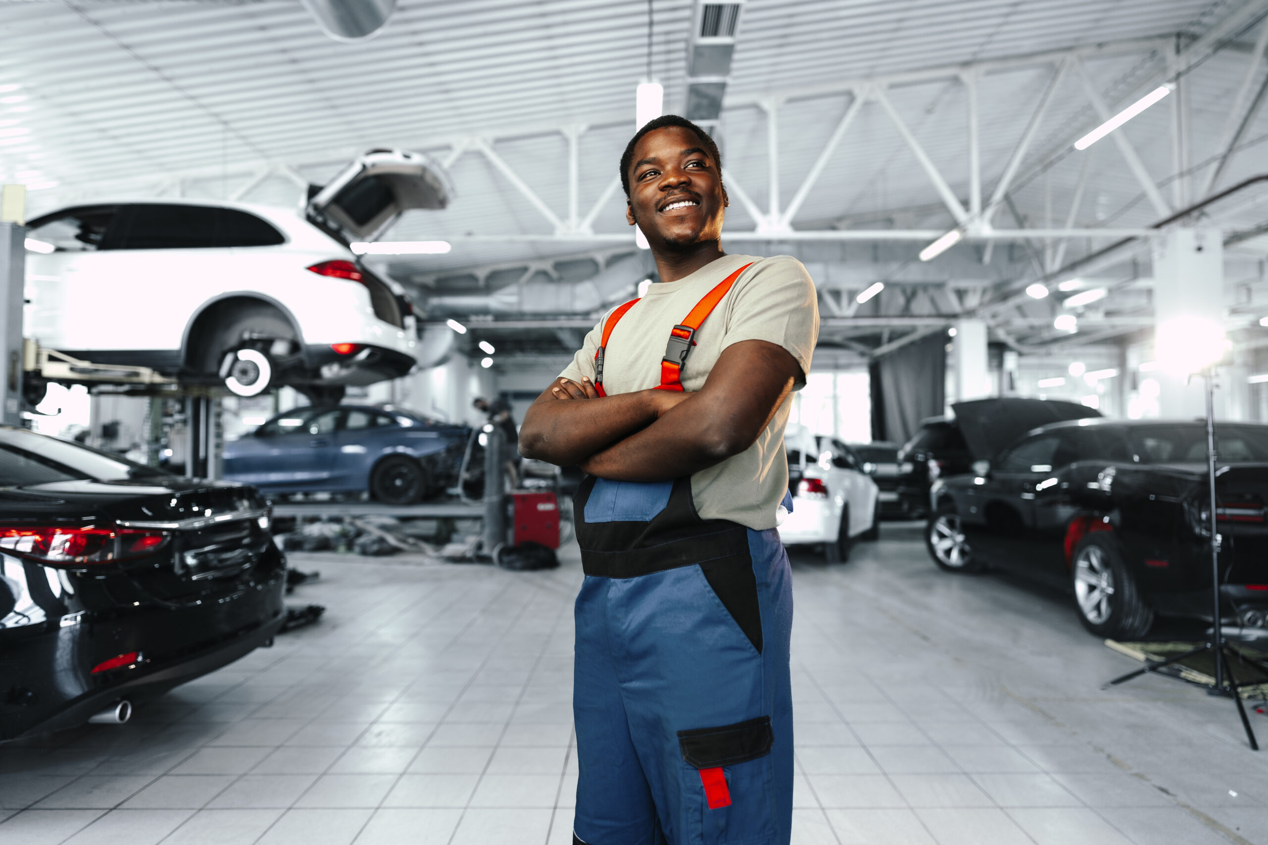 Portrait of a confident African man mechanic in uniform, showcasing his expertise and professionalism in the automotive industry.