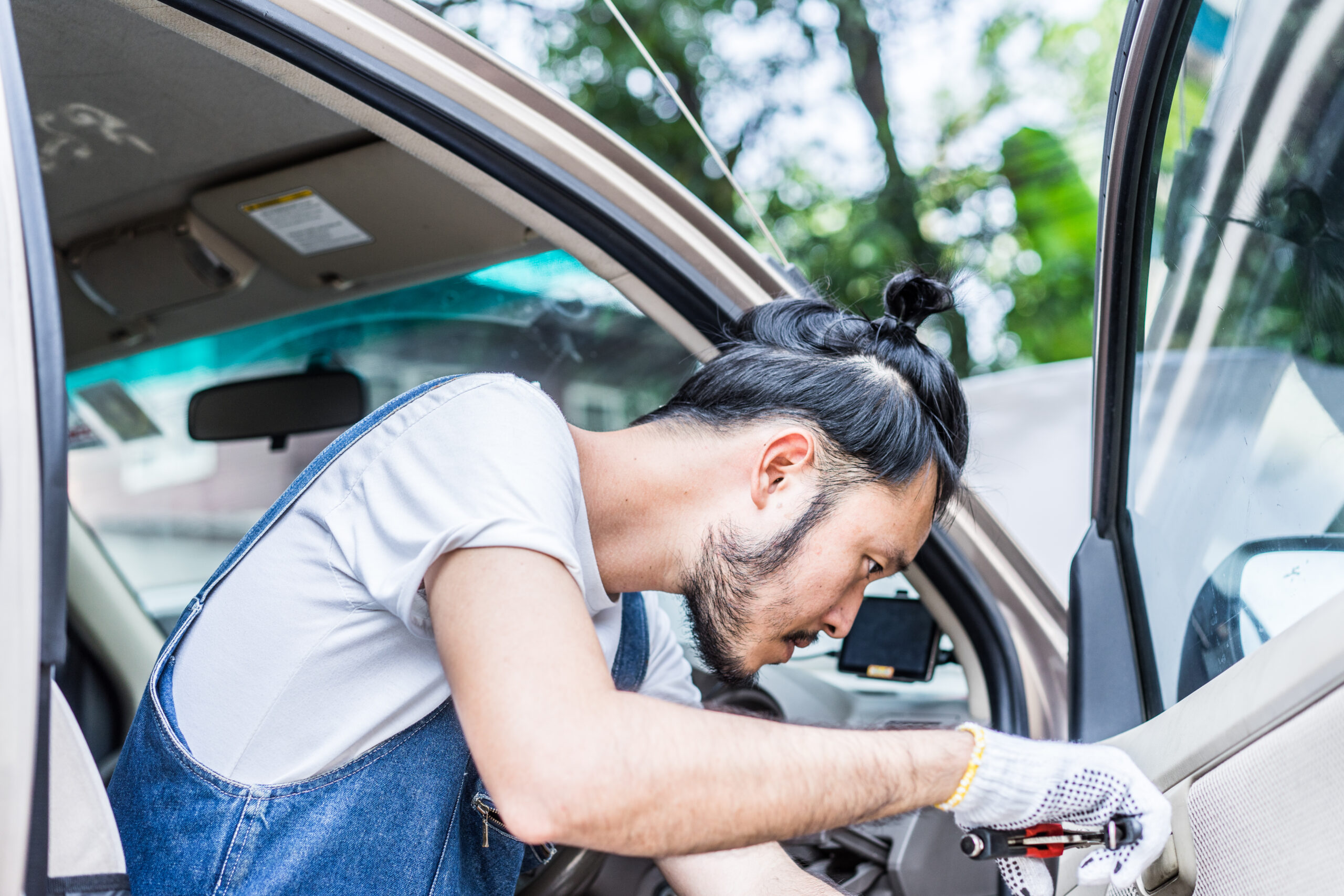 A mechanic in a well-lit repair shop meticulously repairs a car door handle, demonstrating expertise and attention to detail.