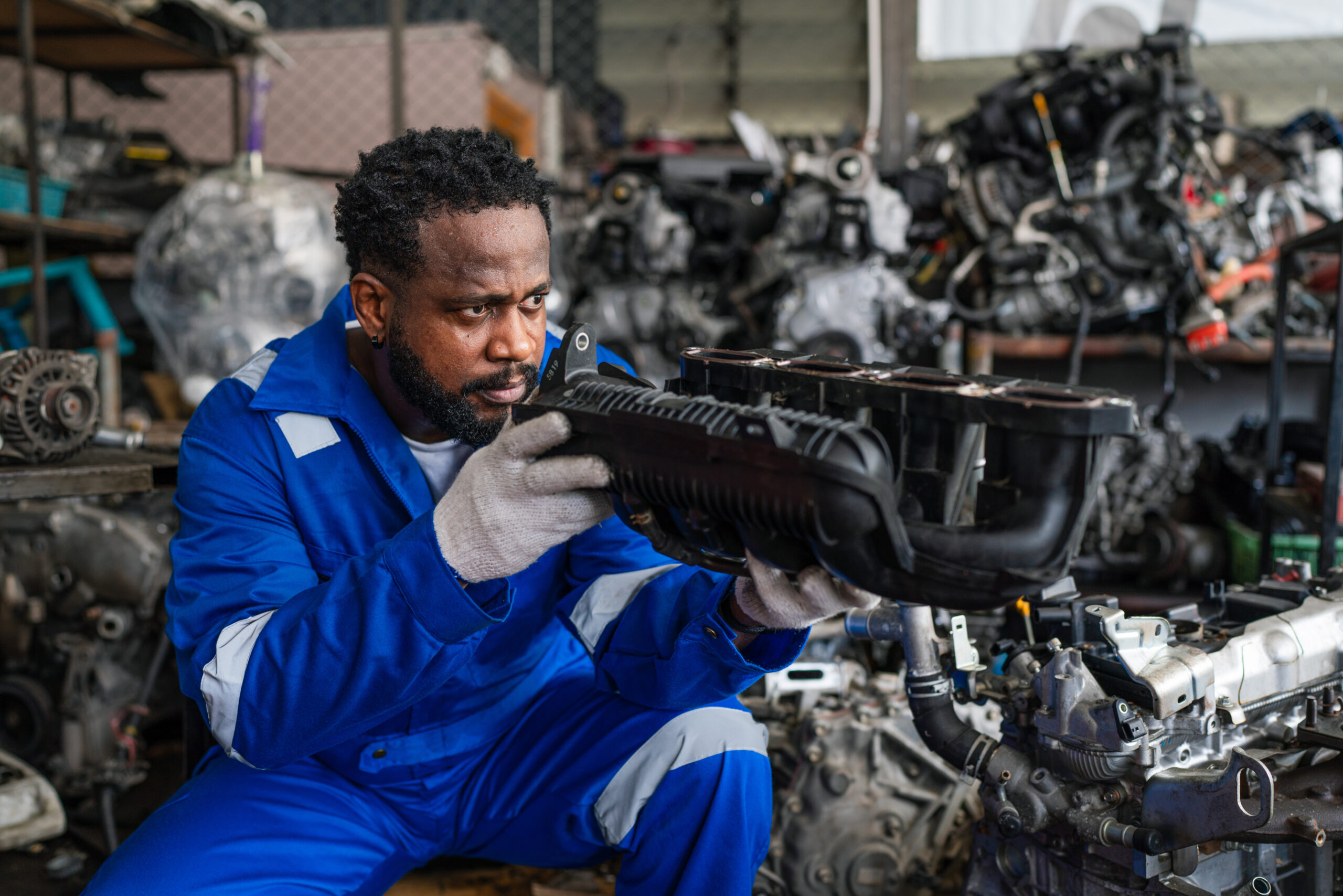 A team of auto mechanics, with tools in hand, diligently works together to troubleshoot and repair a car engine.