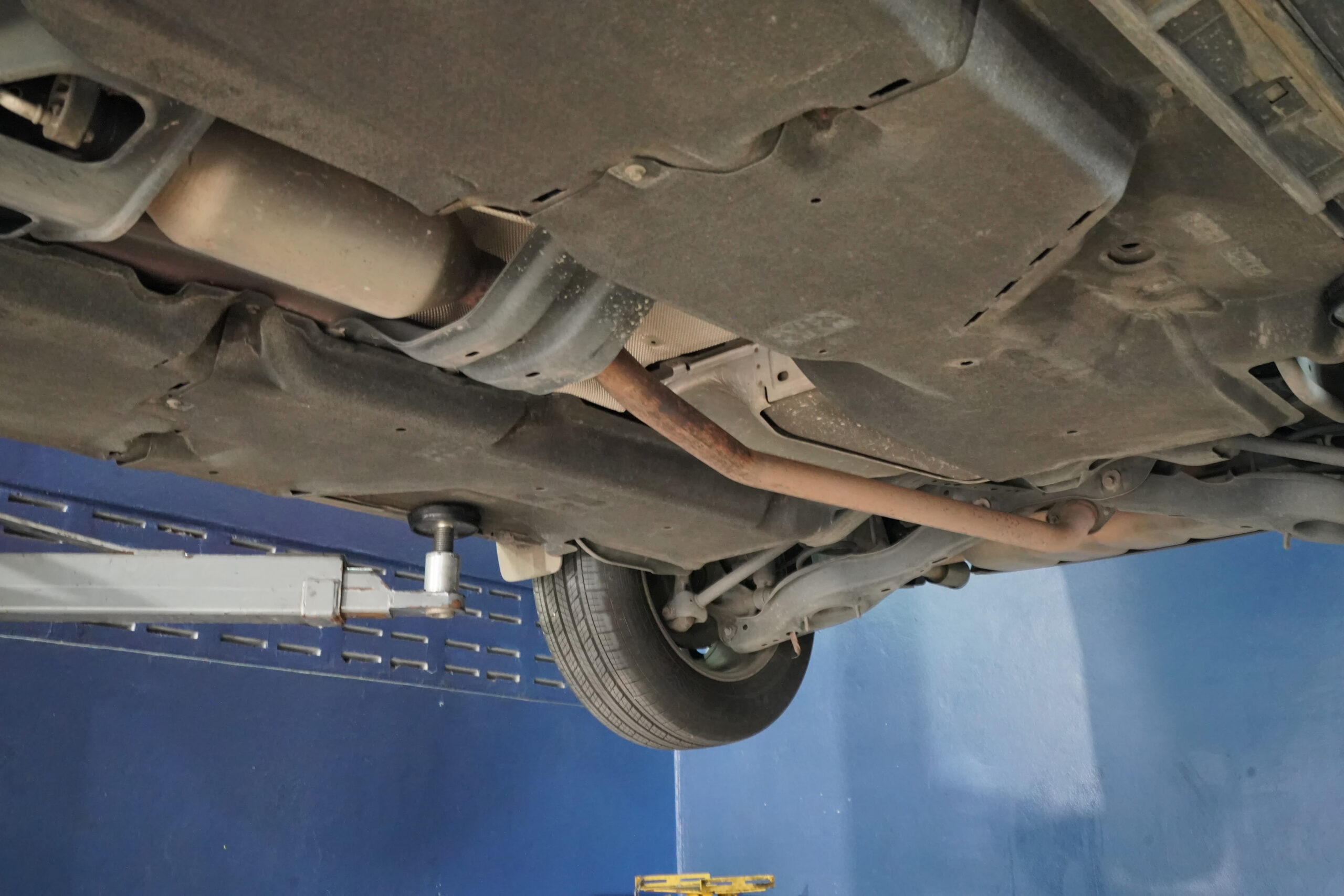 Skilled auto mechanic adjusting a car's wheel alignment using specialized equipment in a professional service garage.