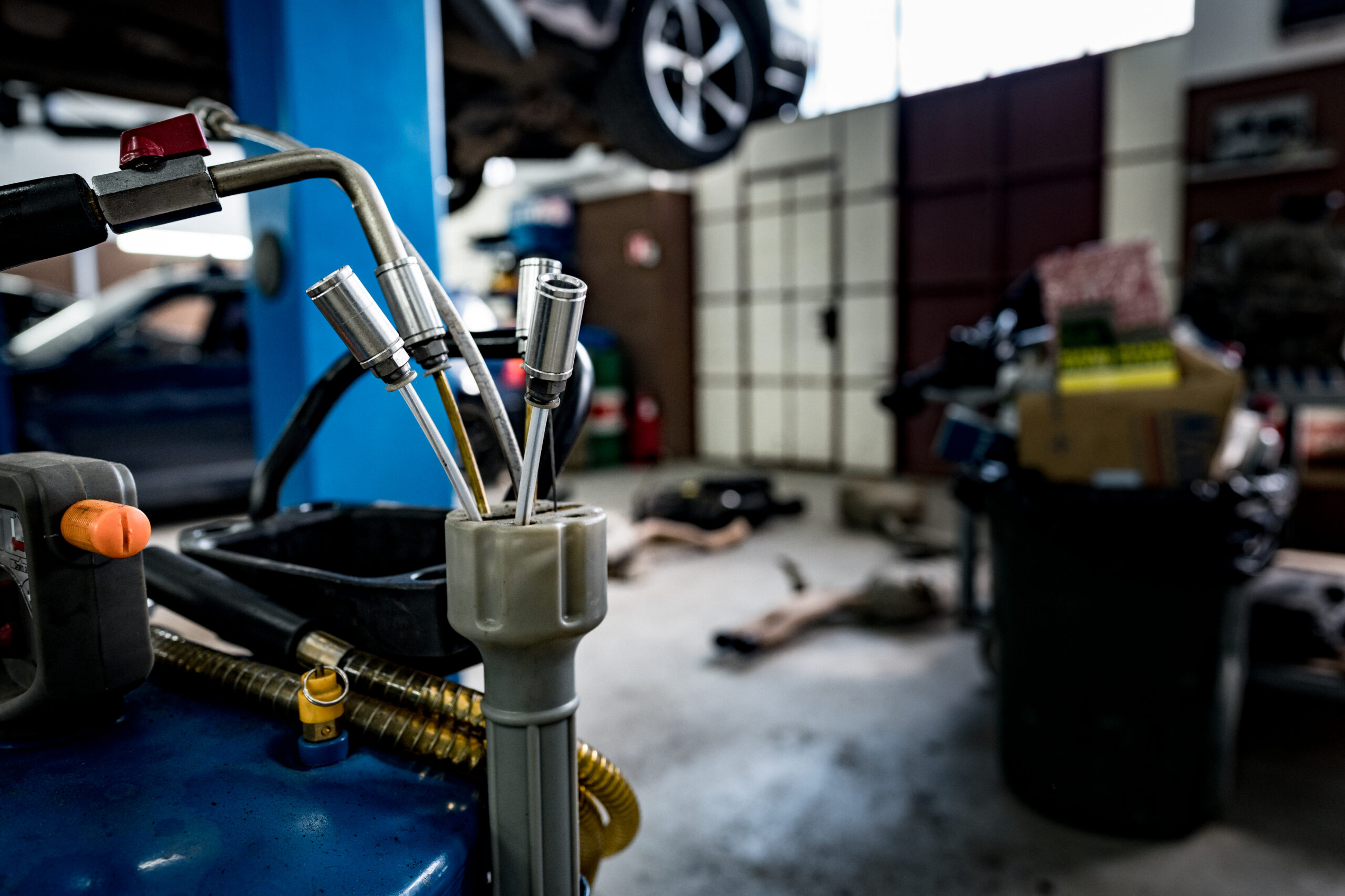 A modern car service center with mechanics working on vehicles in various bays.