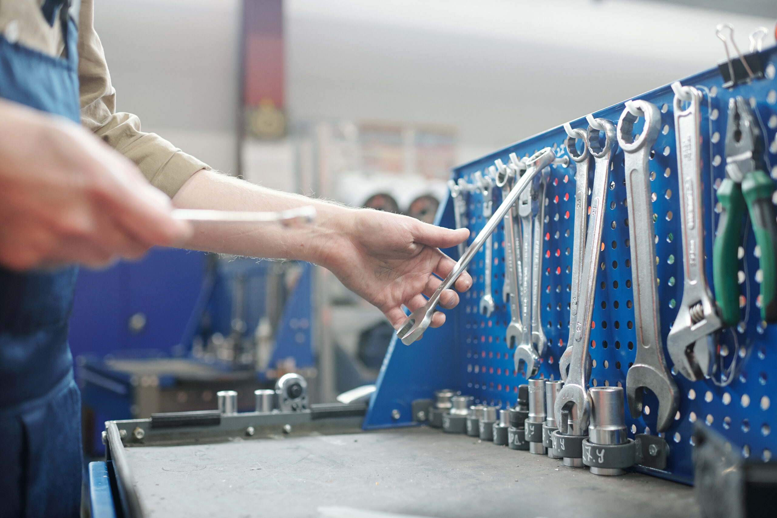 A close-up view of hands holding a toolbox, with a variety of tools laid out on a workbench, ready to be chosen.