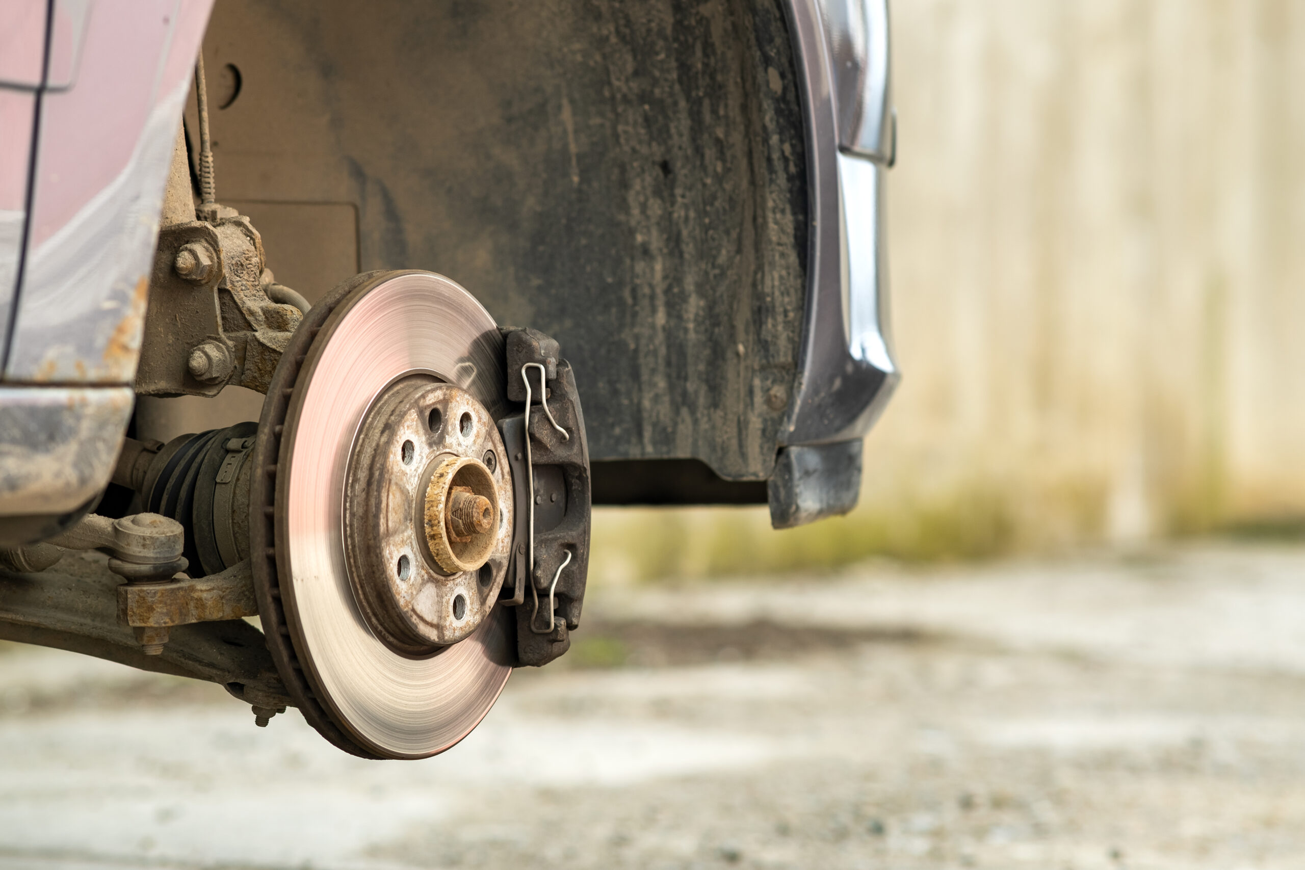 Rusty brake disc and caliper removed from a car for maintenance.