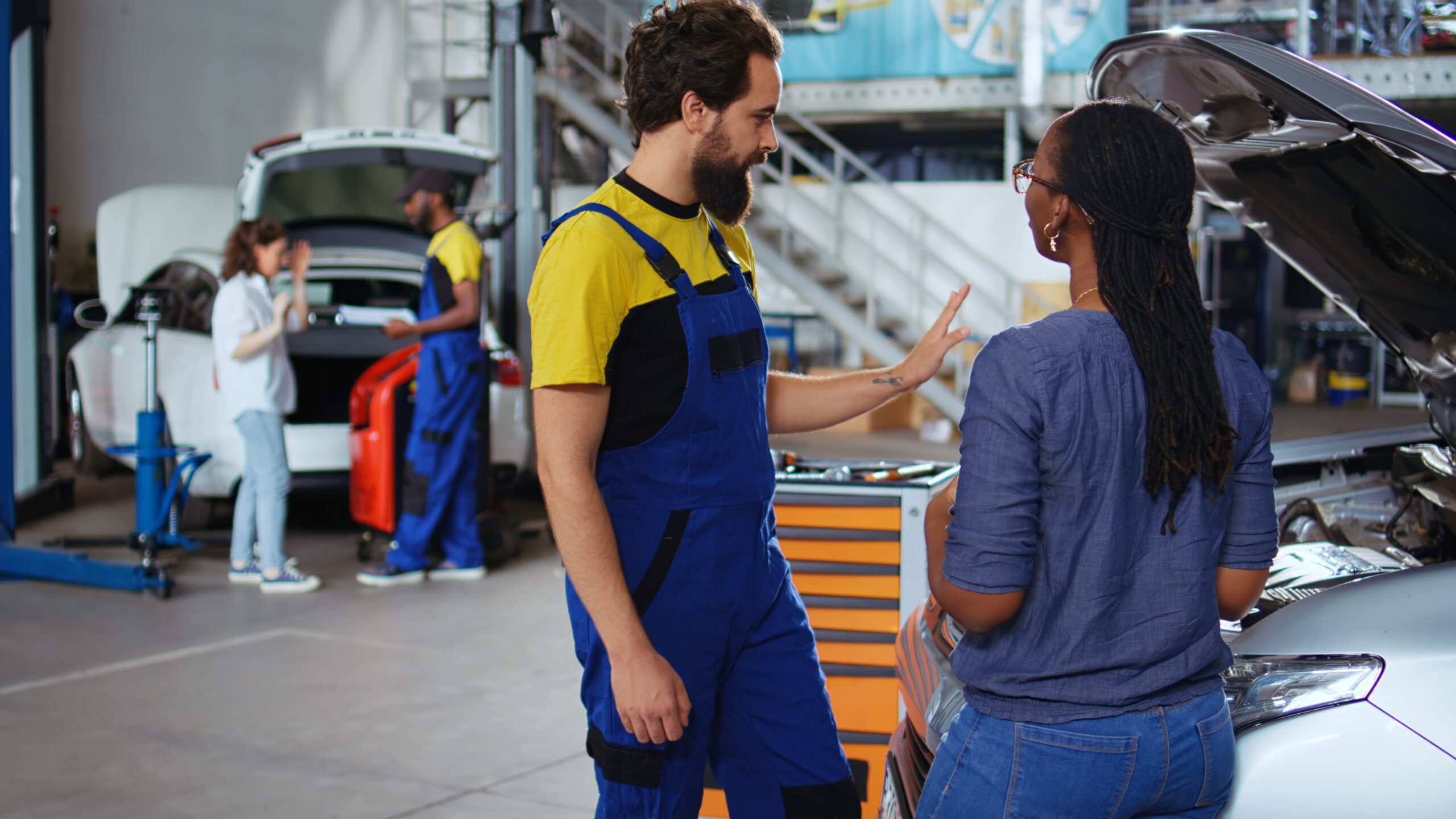 A team of mechanics in a professional garage work together to fix a customer's car, efficiently using their tools and equipment.