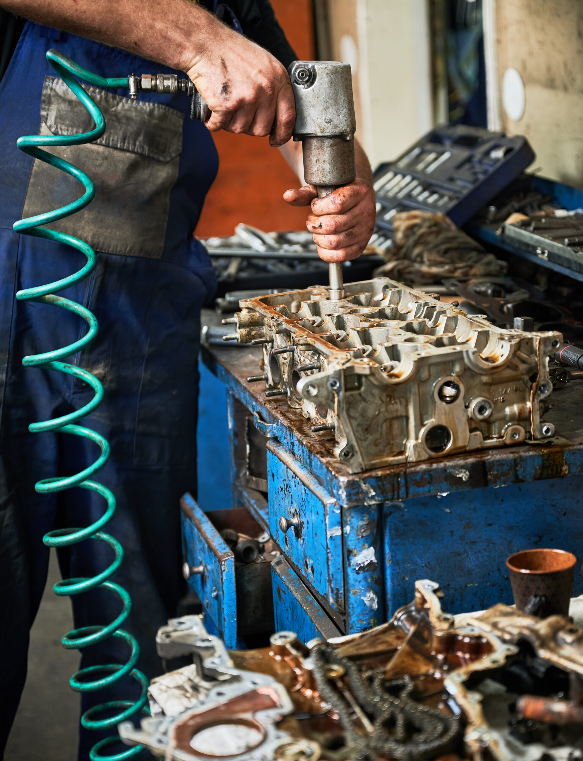 A worker wearing safety gear operates a power drill on a construction site.