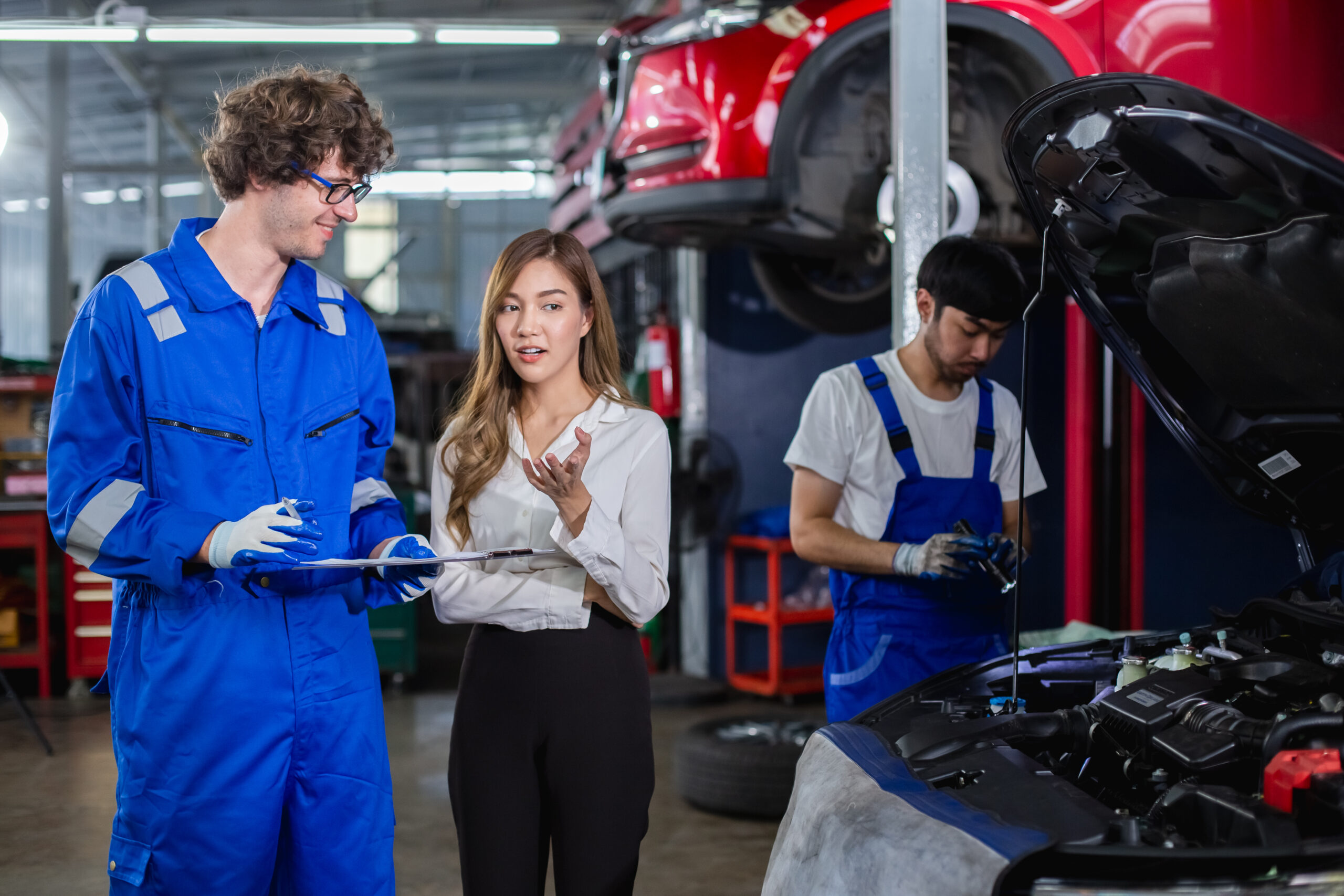 A garage worker explains car repairs to a concerned female customer.