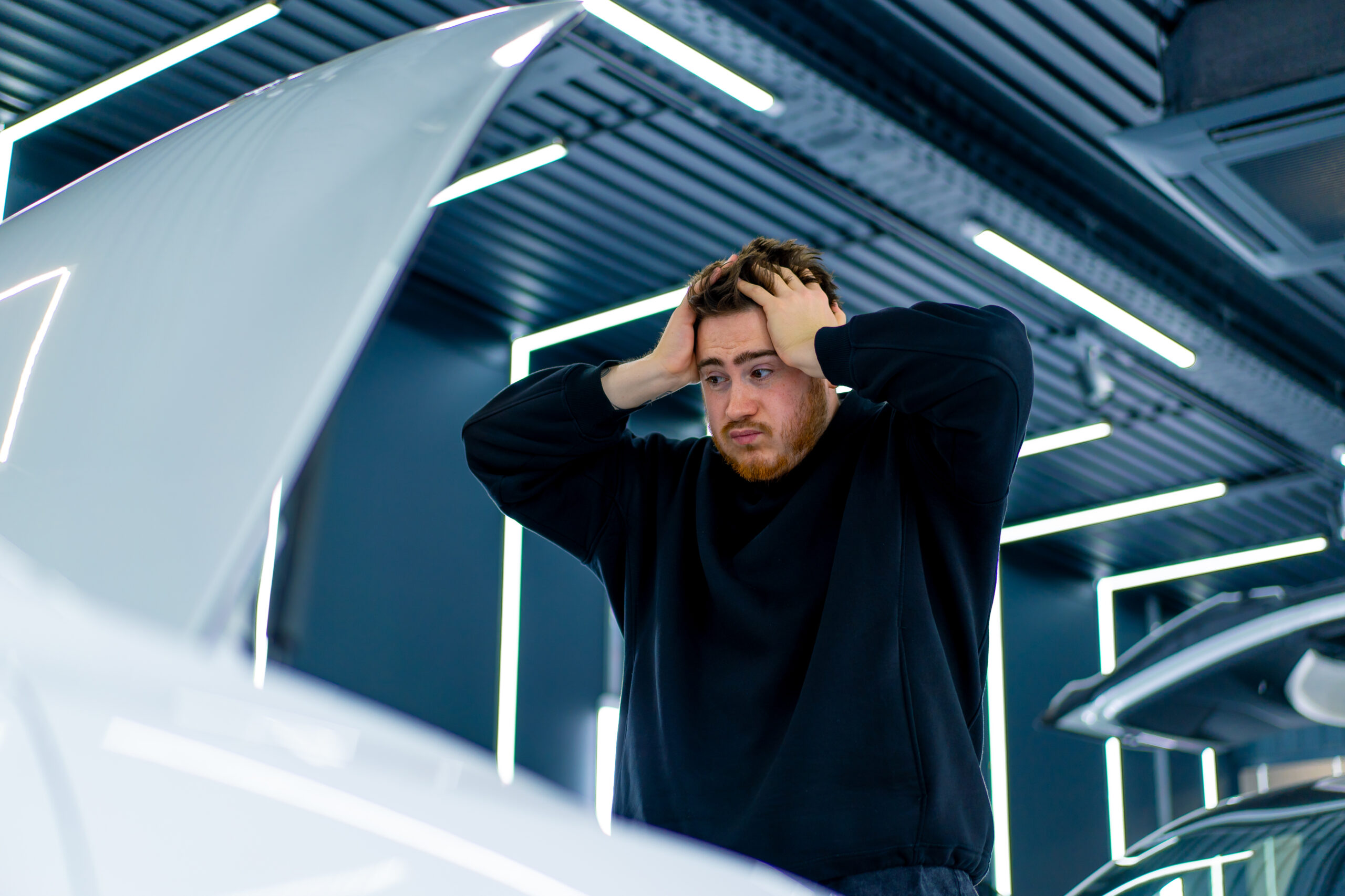 Portrait of a man shocked by the fact that his white luxury car broke down in a parking lot