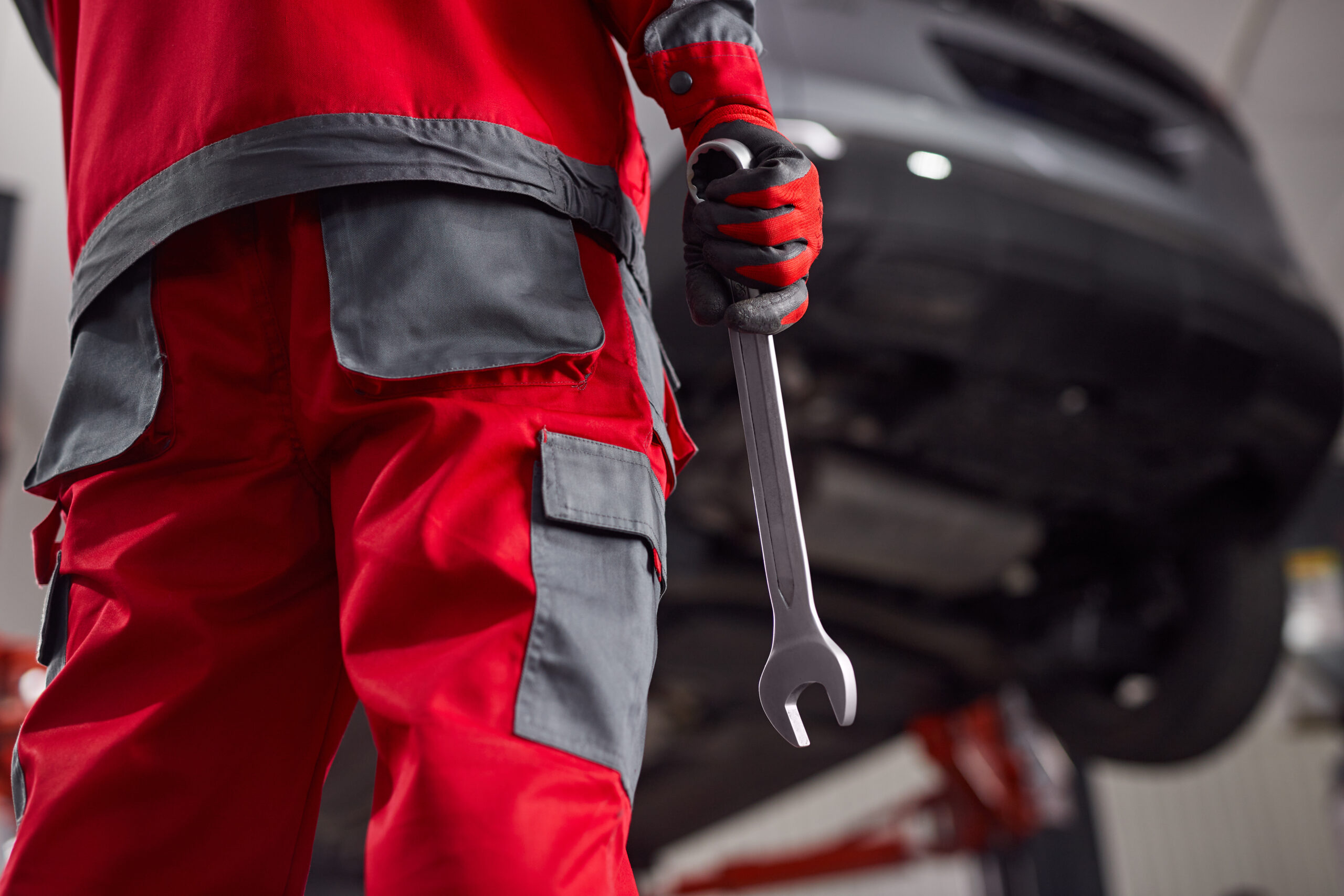 Close-up of a mechanic's hands holding a wrench in a garage.