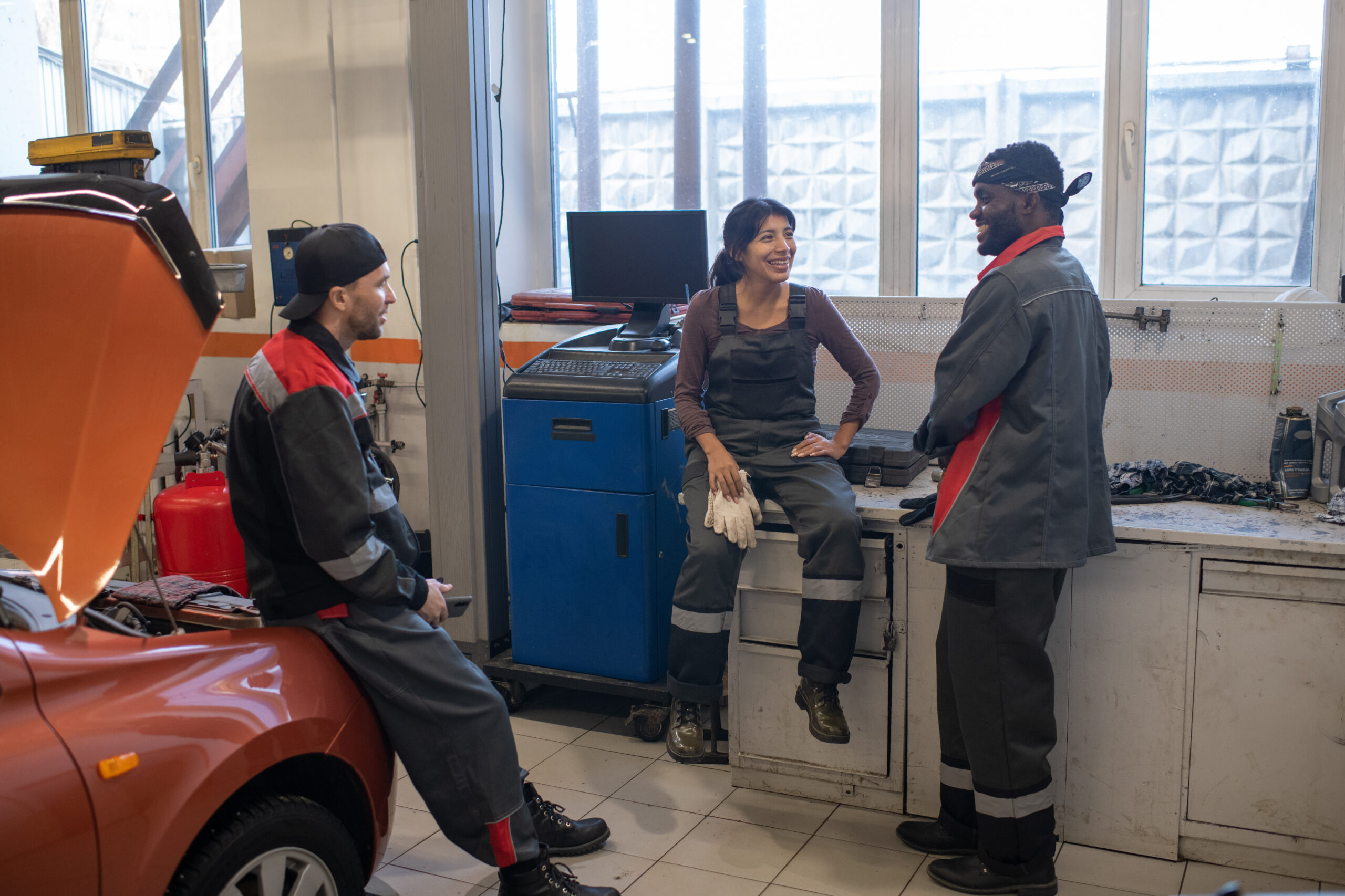 A group of diverse auto mechanics enjoying a well-deserved break in the break room of a car repair shop.